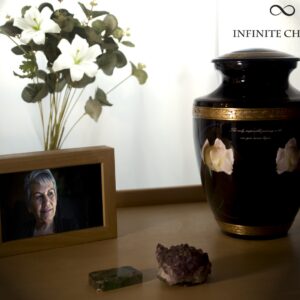 A black urn for ashes with a motorcycle driving to the sea with gold decorations and a picture of my loved one
